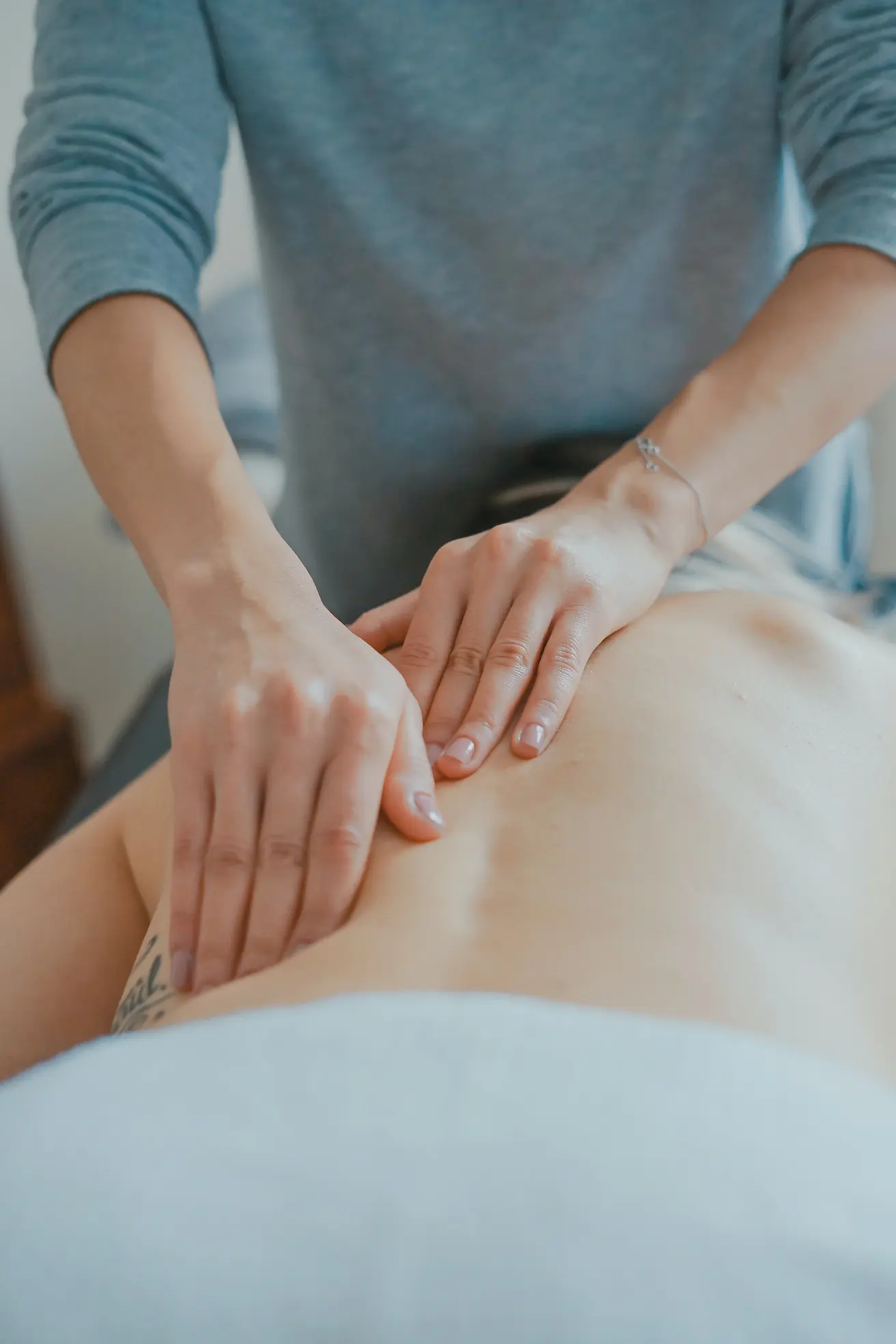 Pair of hands massaging a back.